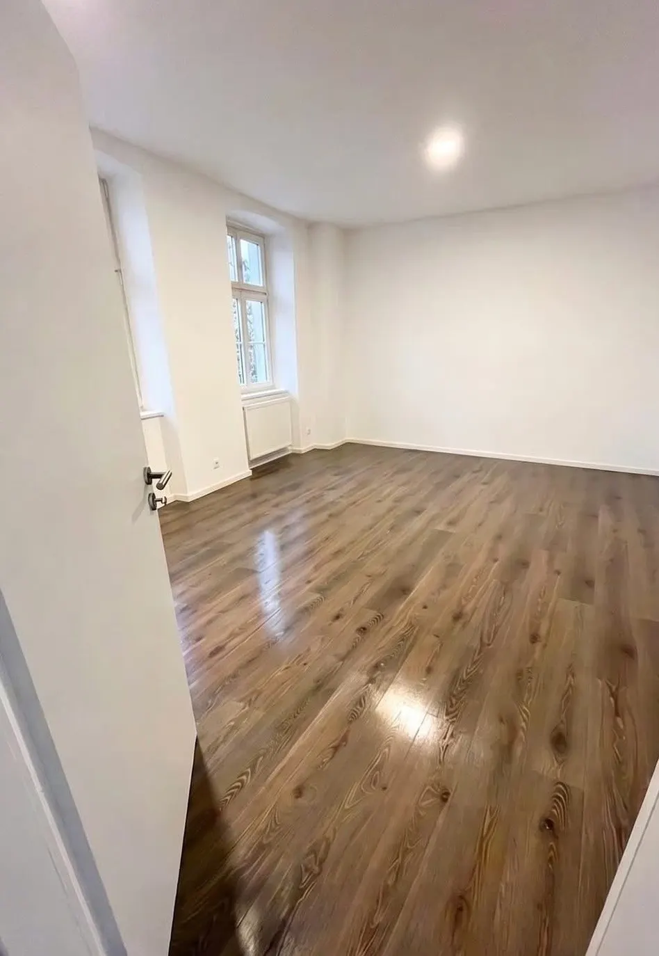 Derselbe Altbauraum mit neu verlegtem Boden in Holzoptik
