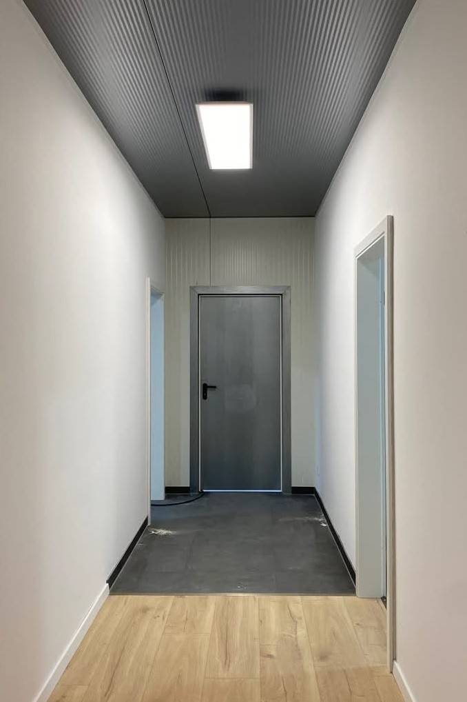 Fertiger Flur mit Holzboden, weißen Wänden und Deckenleuchte