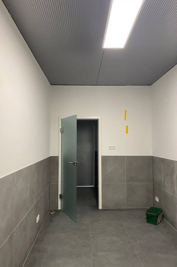 Fertiger Sanitärvorraum mit grauen Fliesen und Glastür