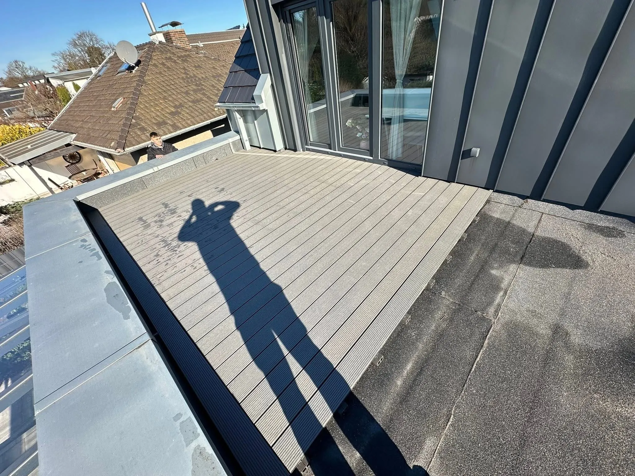 Fertige Dachterrasse mit grauen WPC-Dielen vor einer Fensterfront